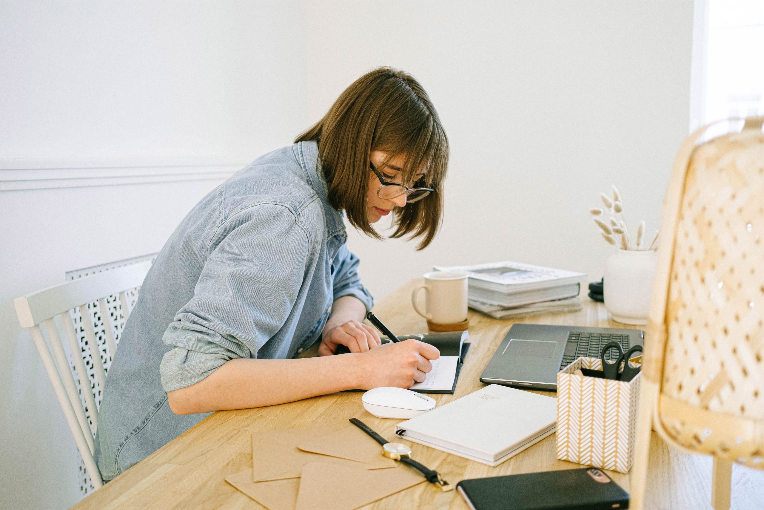 Mujer trabajando desde casa con laptop, agenda y una taza de caf&eacute;