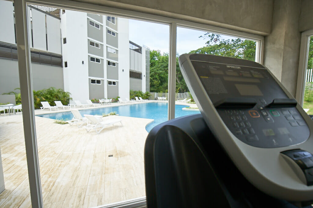 Caminadora en gimnasio con vista a piscina de Pen&iacute;nsula Norte