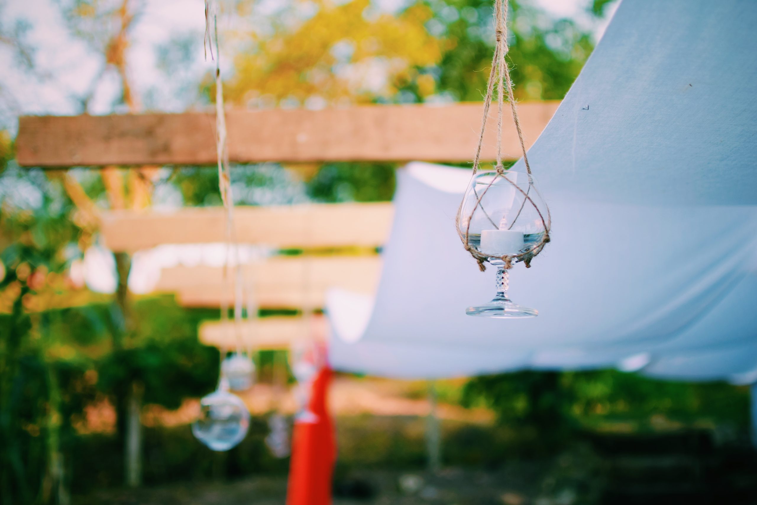 P&eacute;rgola en exteriores decorada con portavelas colgantes hechos de copas de vidrio