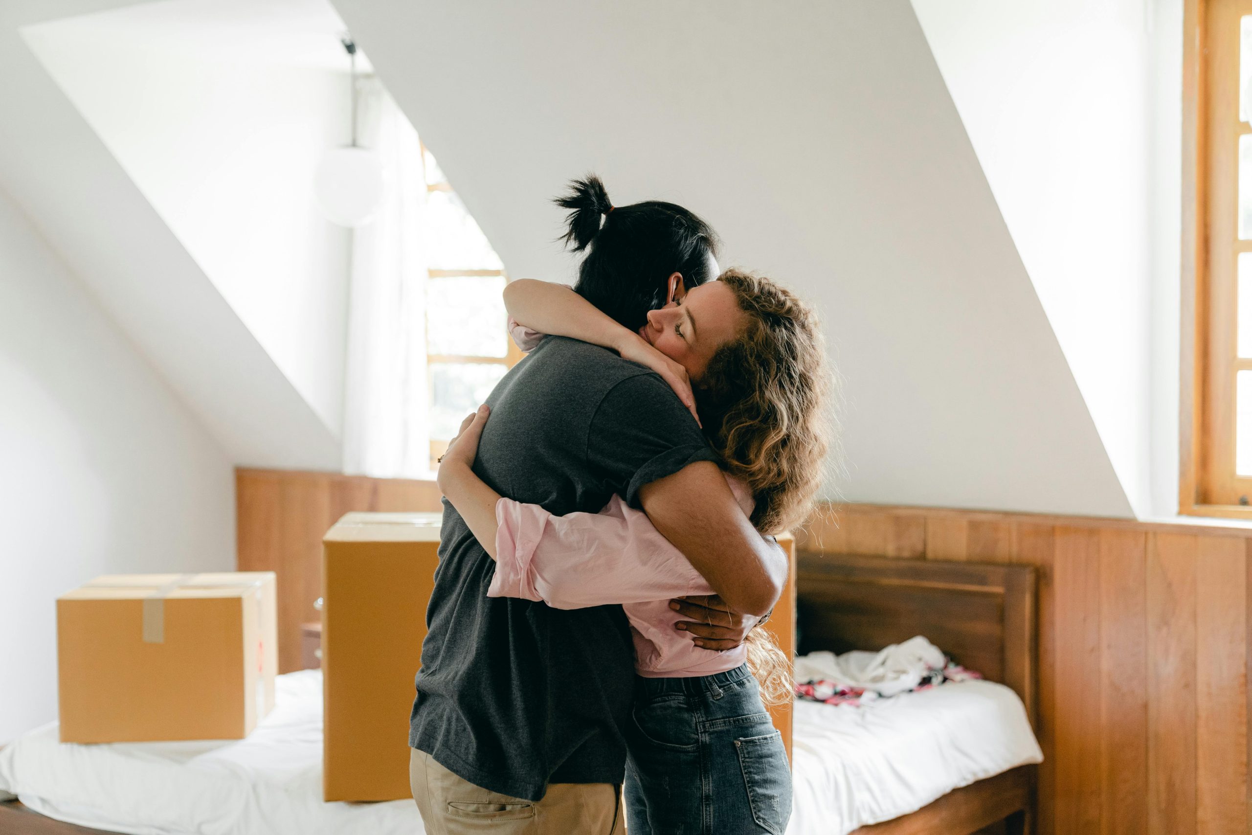 Pareja de esposos abraz&aacute;ndose mientras se mudan a su primera vivienda.