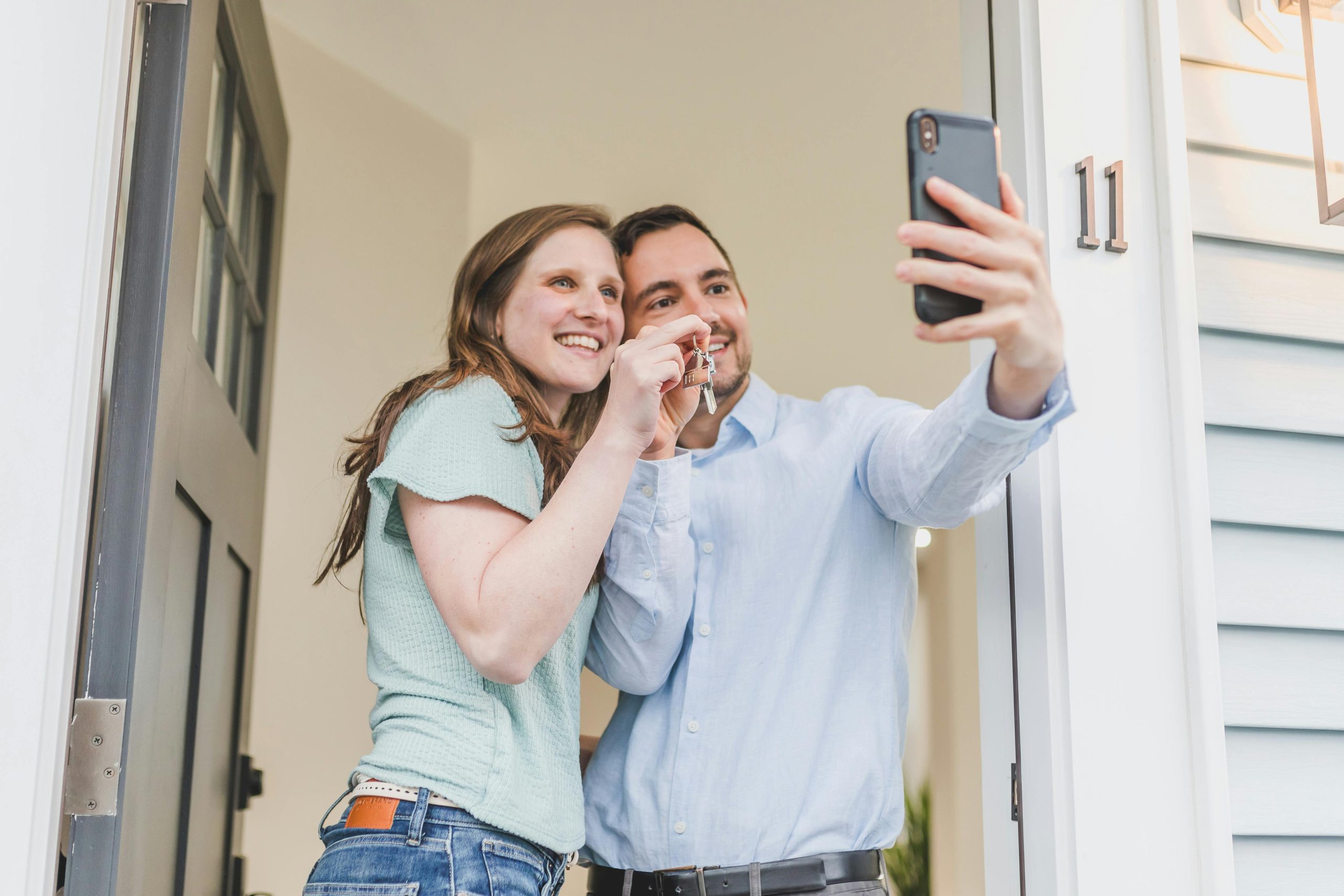 Pareja tom&aacute;ndose una selfie mientras sostiene la llave de su nuevo hogar.