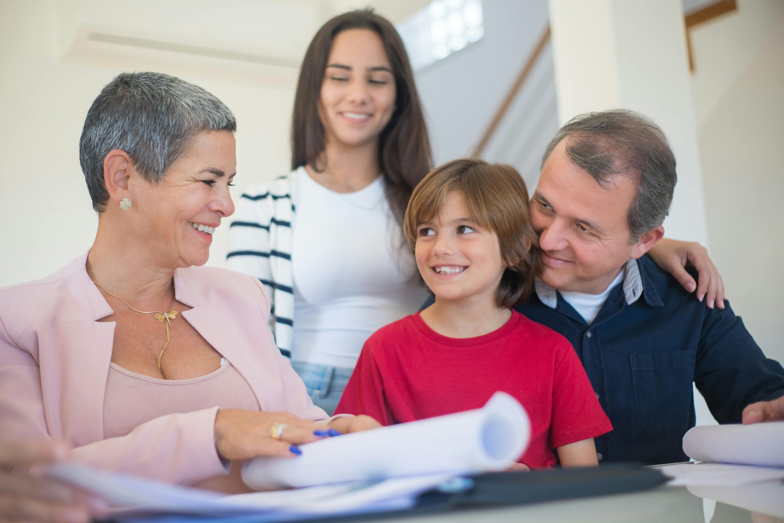 Familia analizando plan financiero con asesora de bienes ra&iacute;ces.