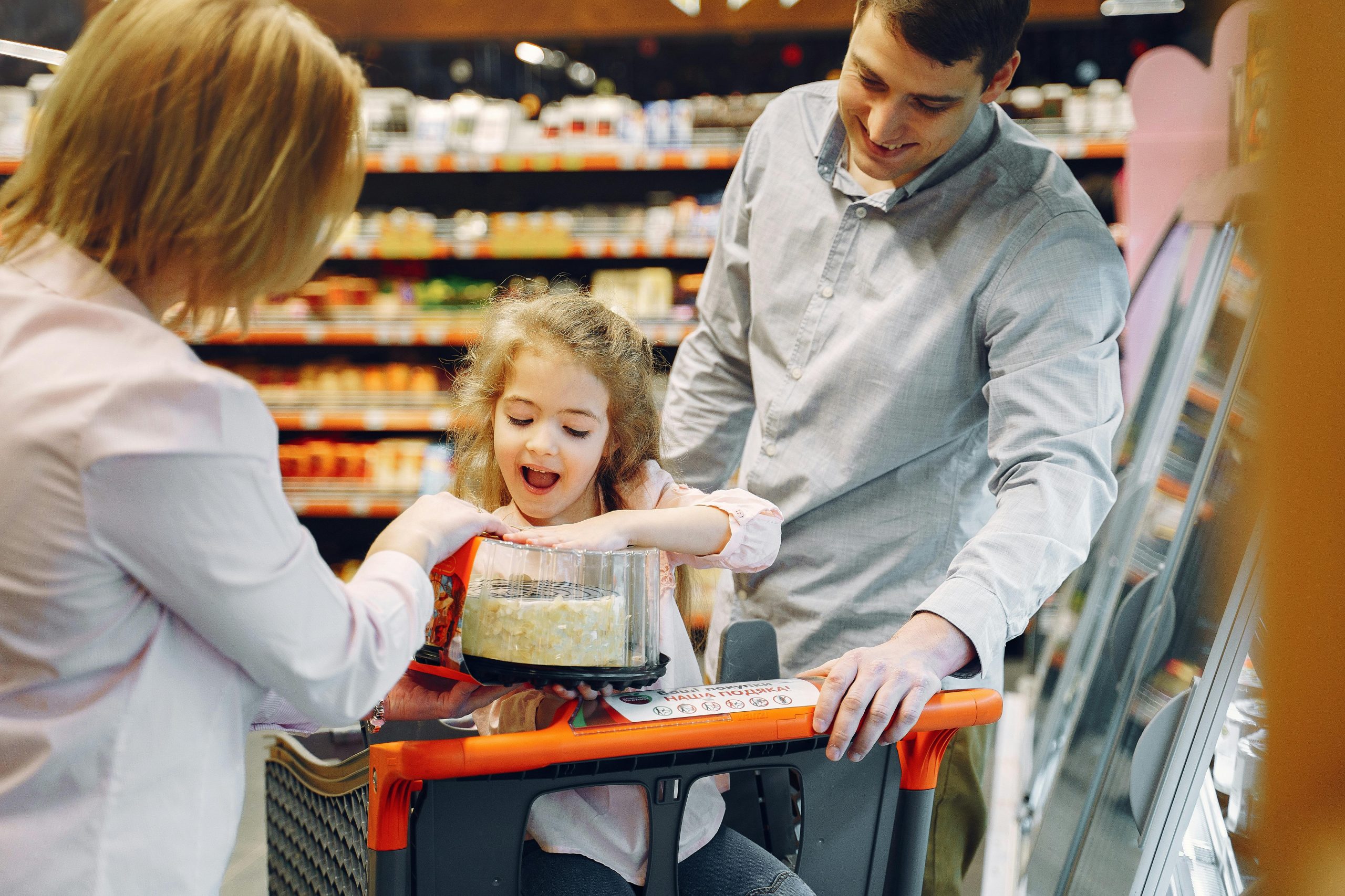 Ni&ntilde;a feliz comprando un pastel con sus padres