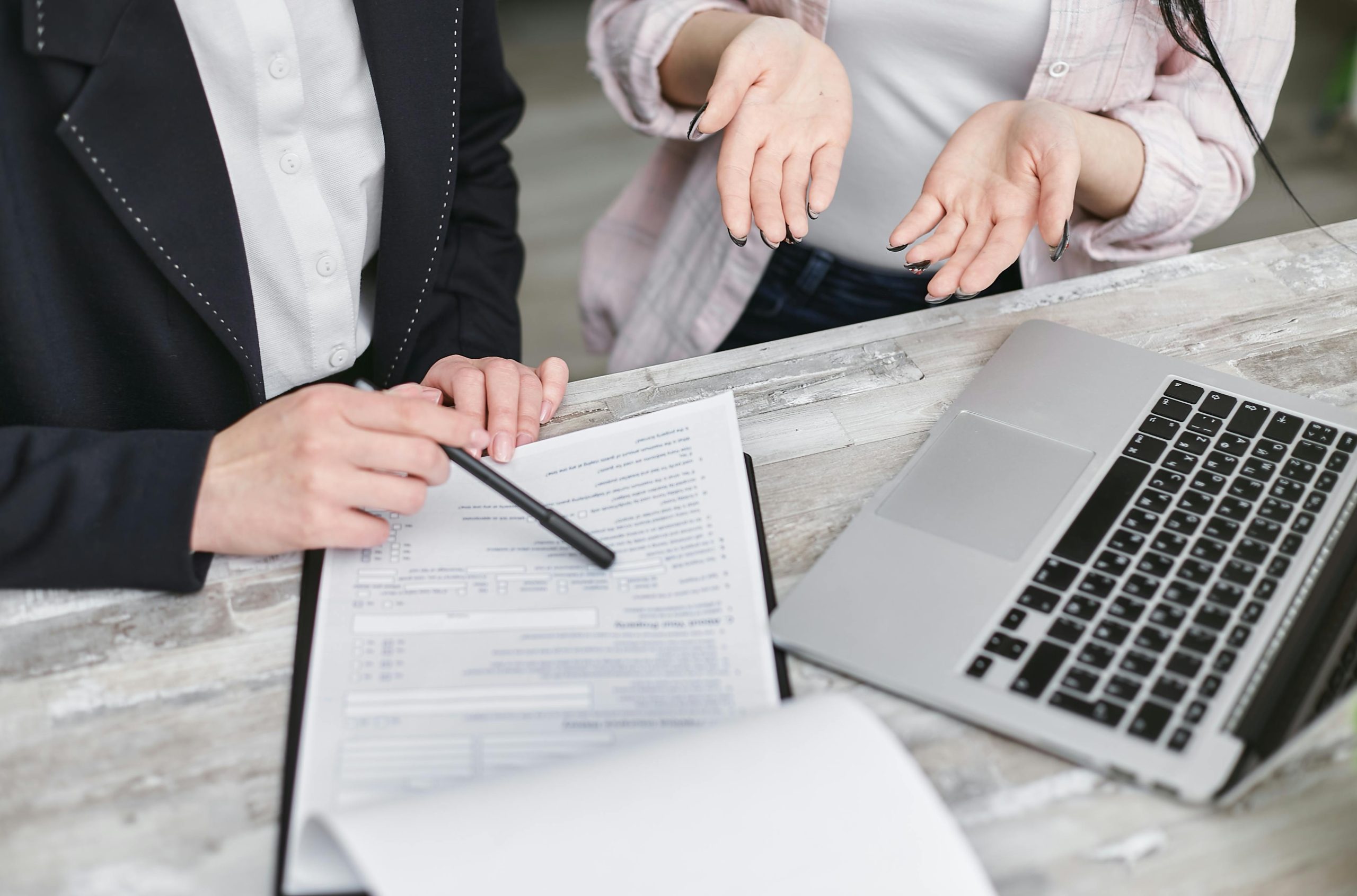 Dos personas frente a contrato y computadora calculando pr&eacute;stamos hipotecarios.