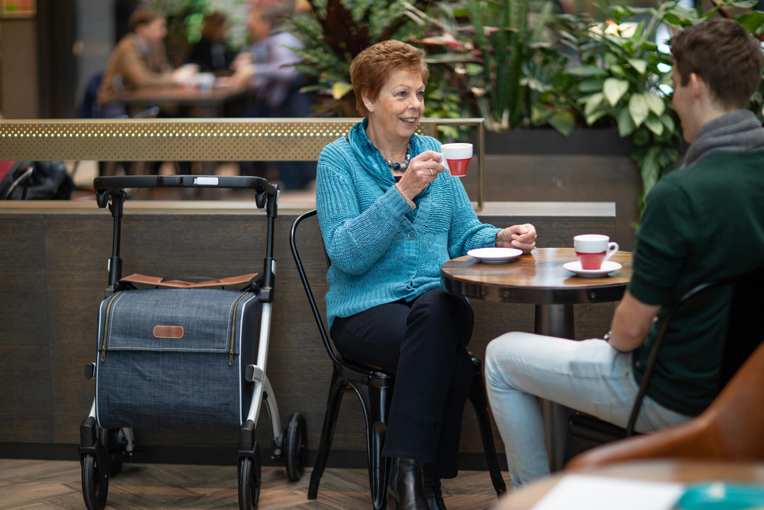 Dos personas sentadas tom&aacute;ndose un caf&eacute; en centro comercial.
