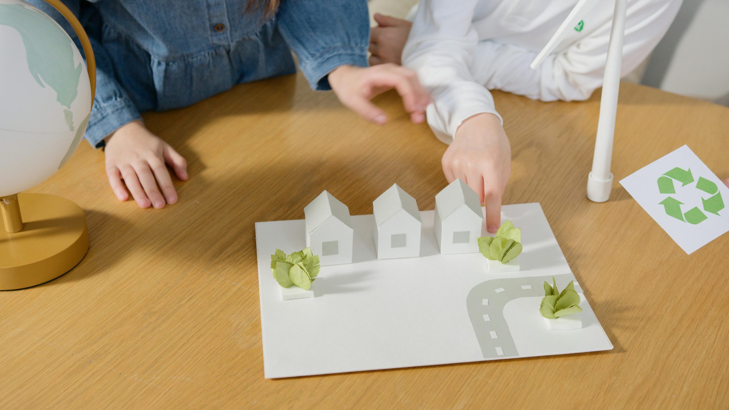 Ni&ntilde;os jugando con tablero con casas, camino y plantas.