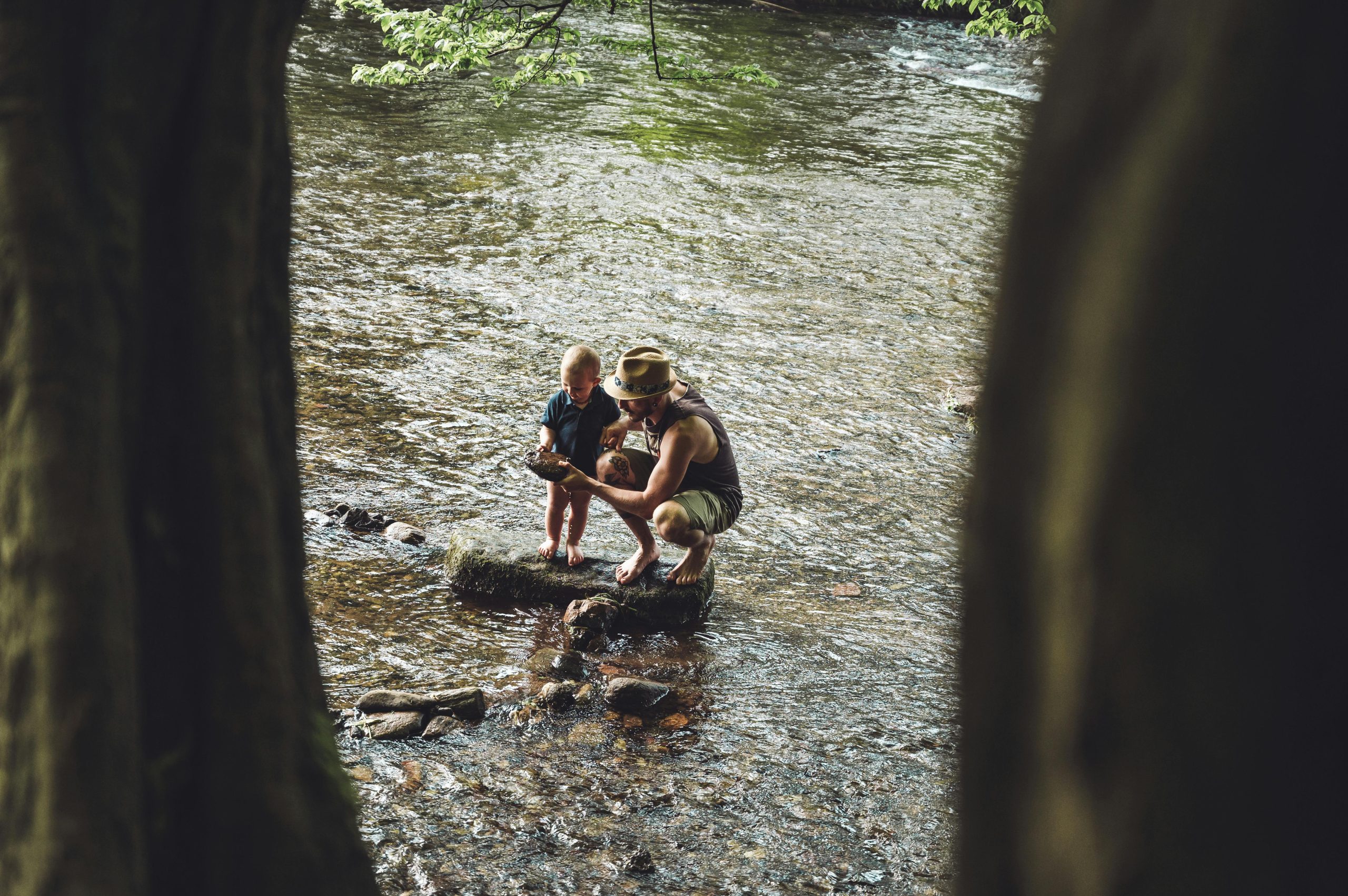 Padre e hijo explorando la orilla de un r&iacute;o.