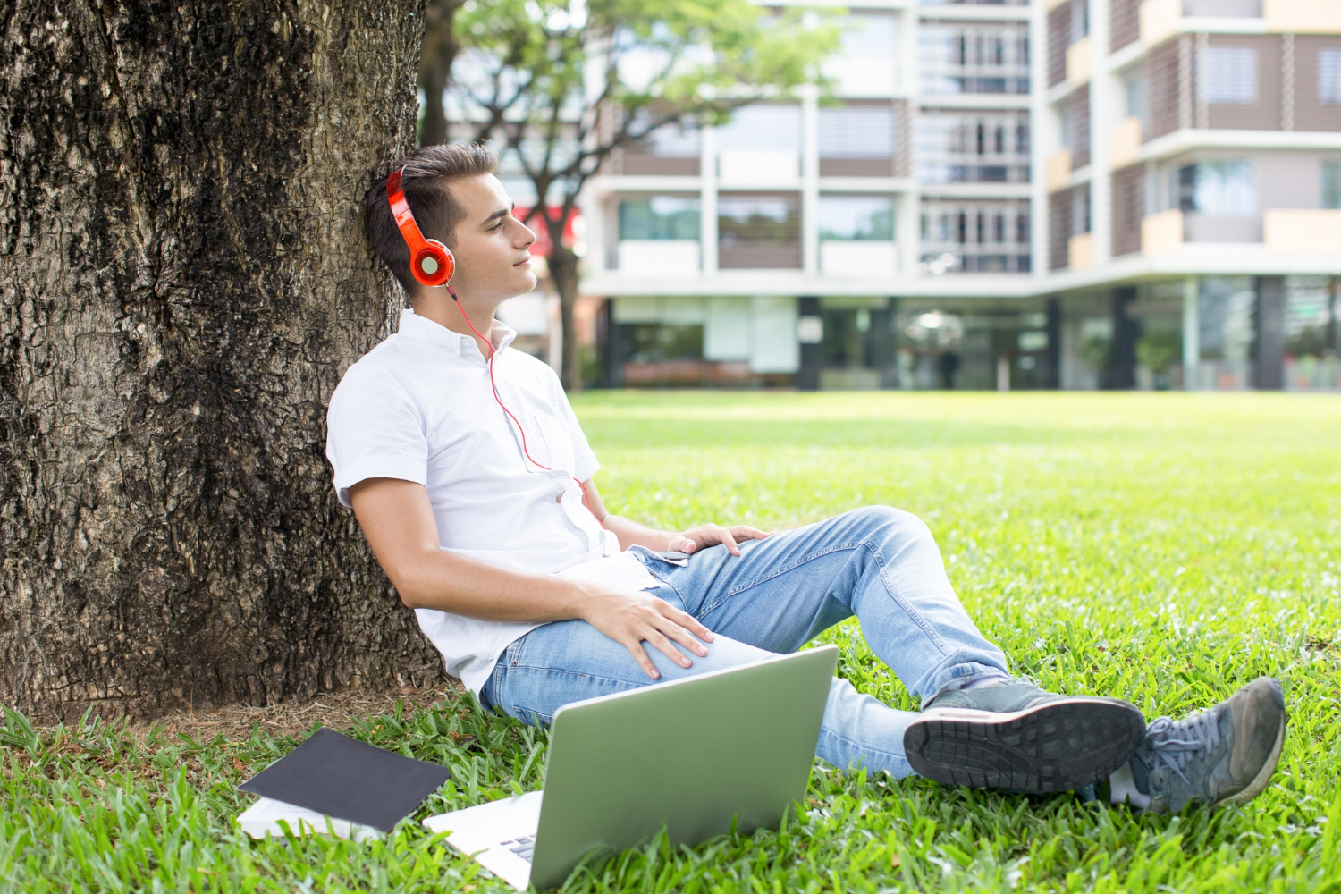 Joven con laptop y aud&iacute;fonos en un urbanismo cotidiano